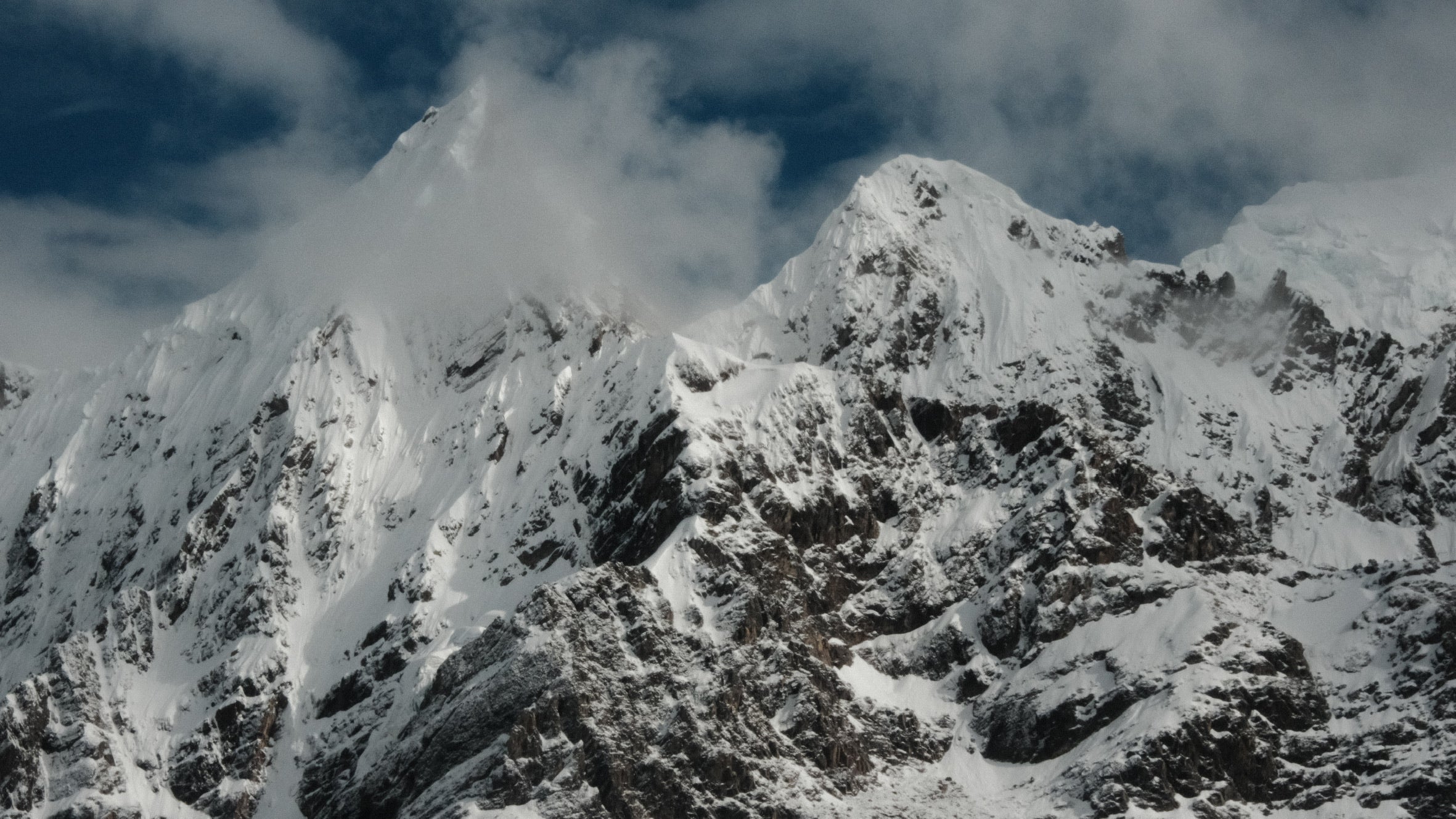 Snow-covered mountain peaks with clouds in the sky