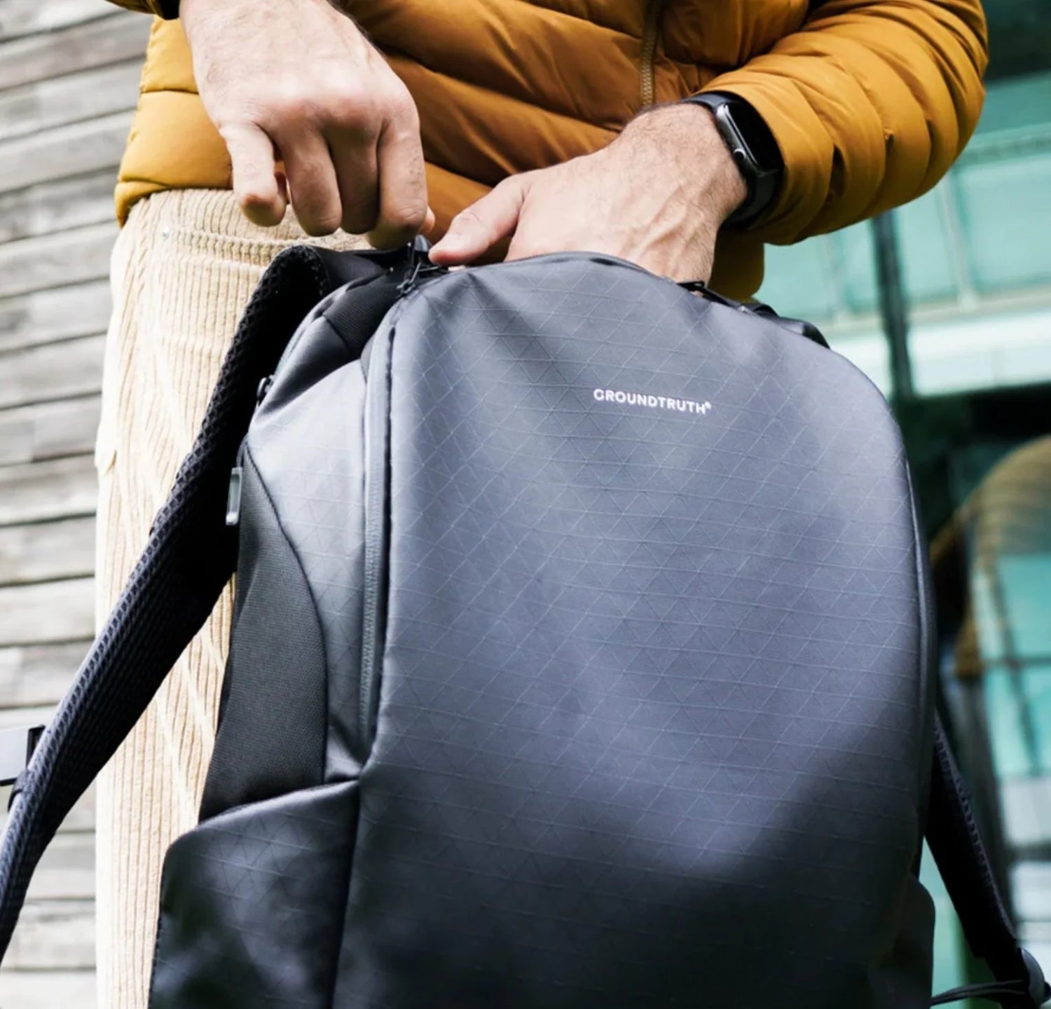 Person holding a black Groundtruth backpack coated with PolyCores Eco-Shield.